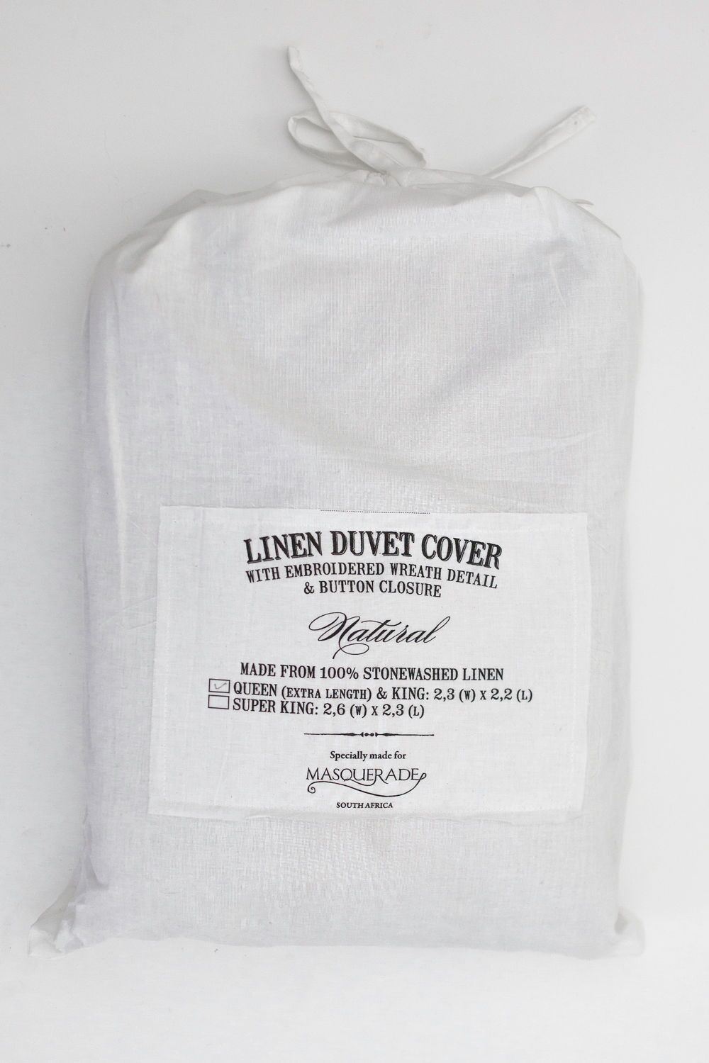 White linen duvet cover in a fabric bag with a tied top and a label listing sizes and care details.