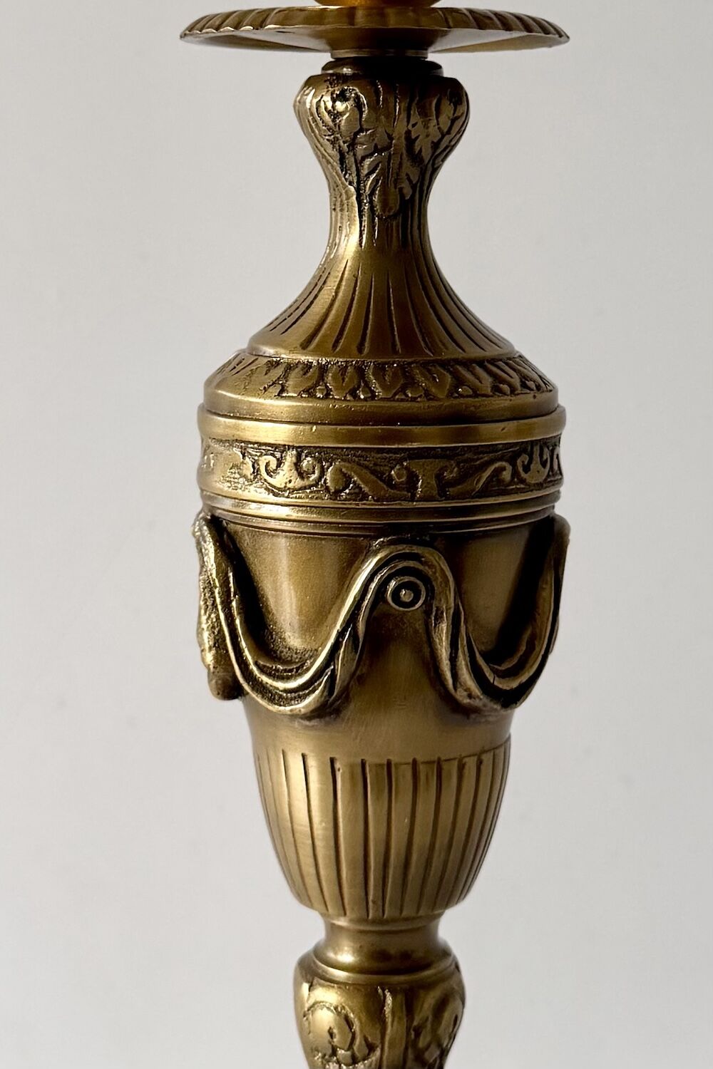 Ornate gold brass lamp base with a carved mask motif and decorative scrollwork on the band.