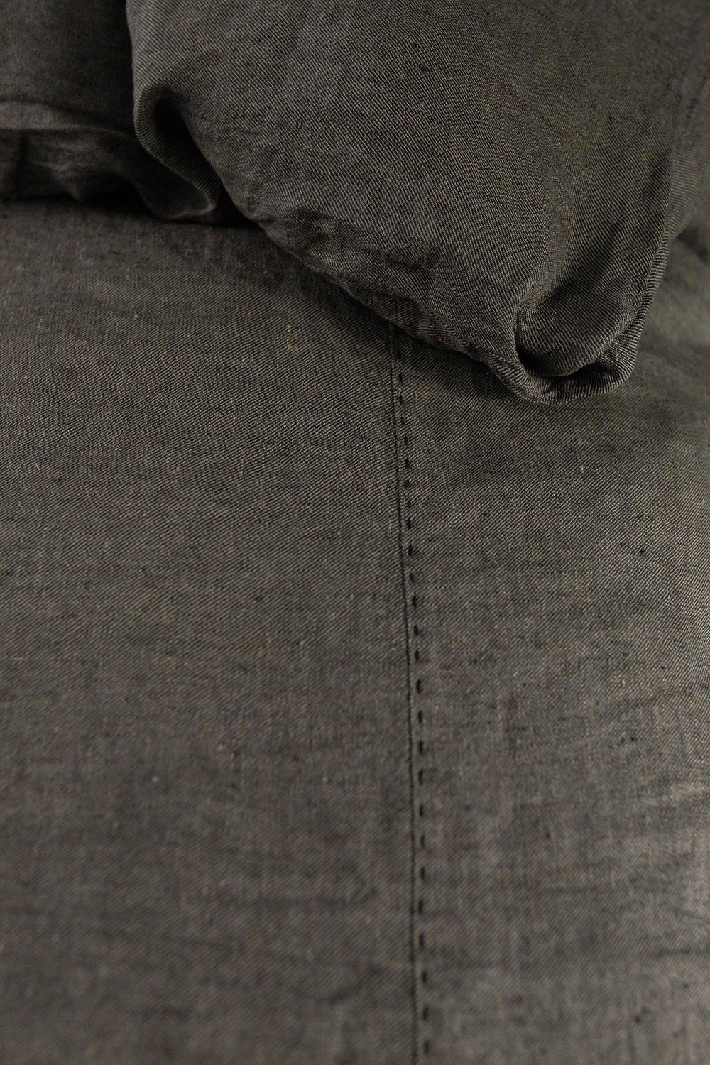 Close-up of dark gray denim fabric with a vertical seam and a folded hood at the top.